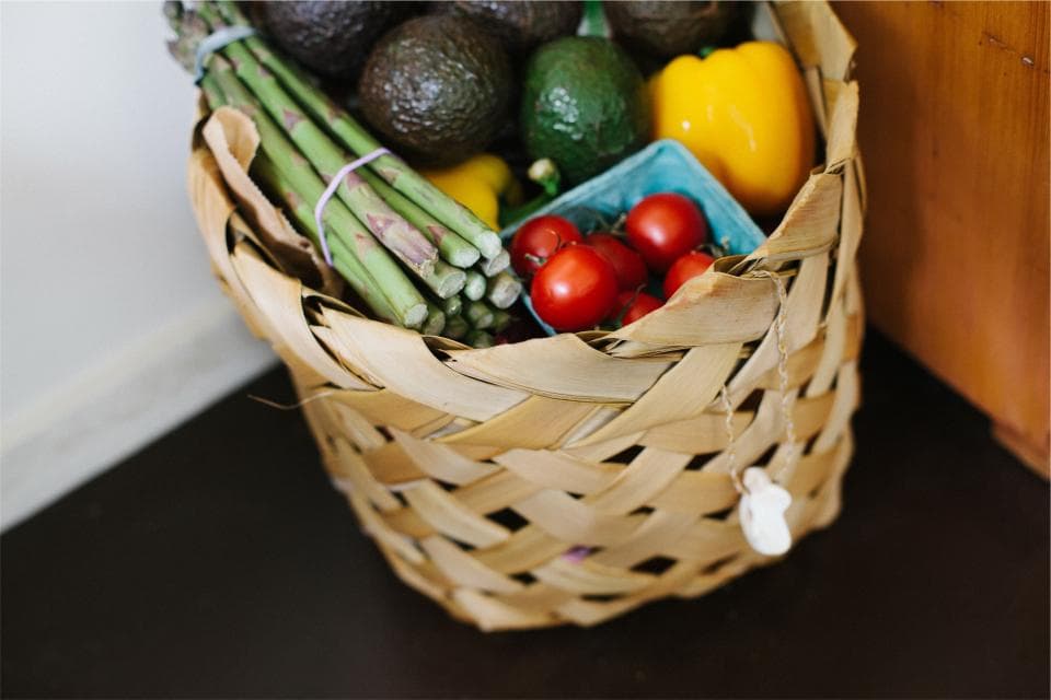 Basket of fresh groceries including peppers, avocados and asparagus