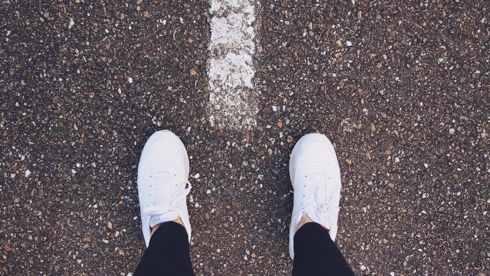 Pair of white sneakers on an asphalt road