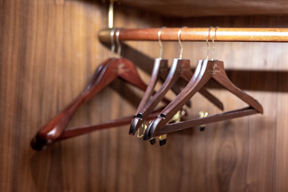 Wooden hangers on a clothing rail in a minimalist closet