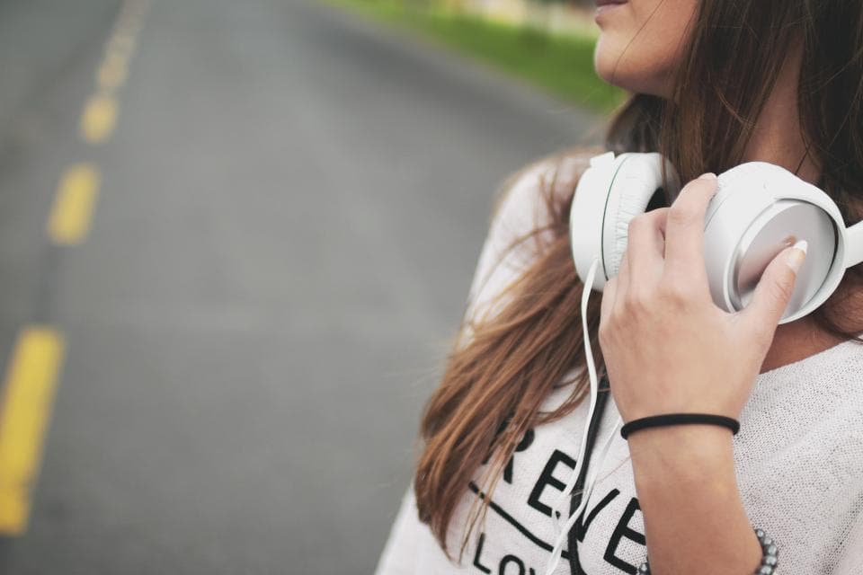 Woman holding a pair of white over-ear headphones