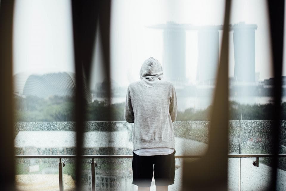 Person in a grey hoodie looking out over a city skyline